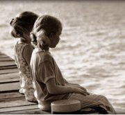 two young girls sitting on a dock