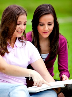 two teen girls reading a book